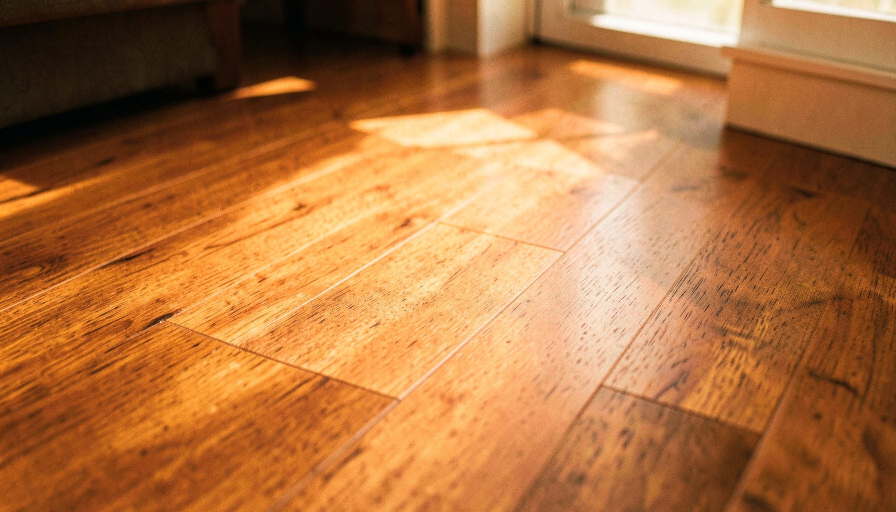 Warm-toned wood-plastic composite flooring planks in a sunlit interior, rich brown and honey hues with subtle grain texture, conveying natural warmth and modern durability.